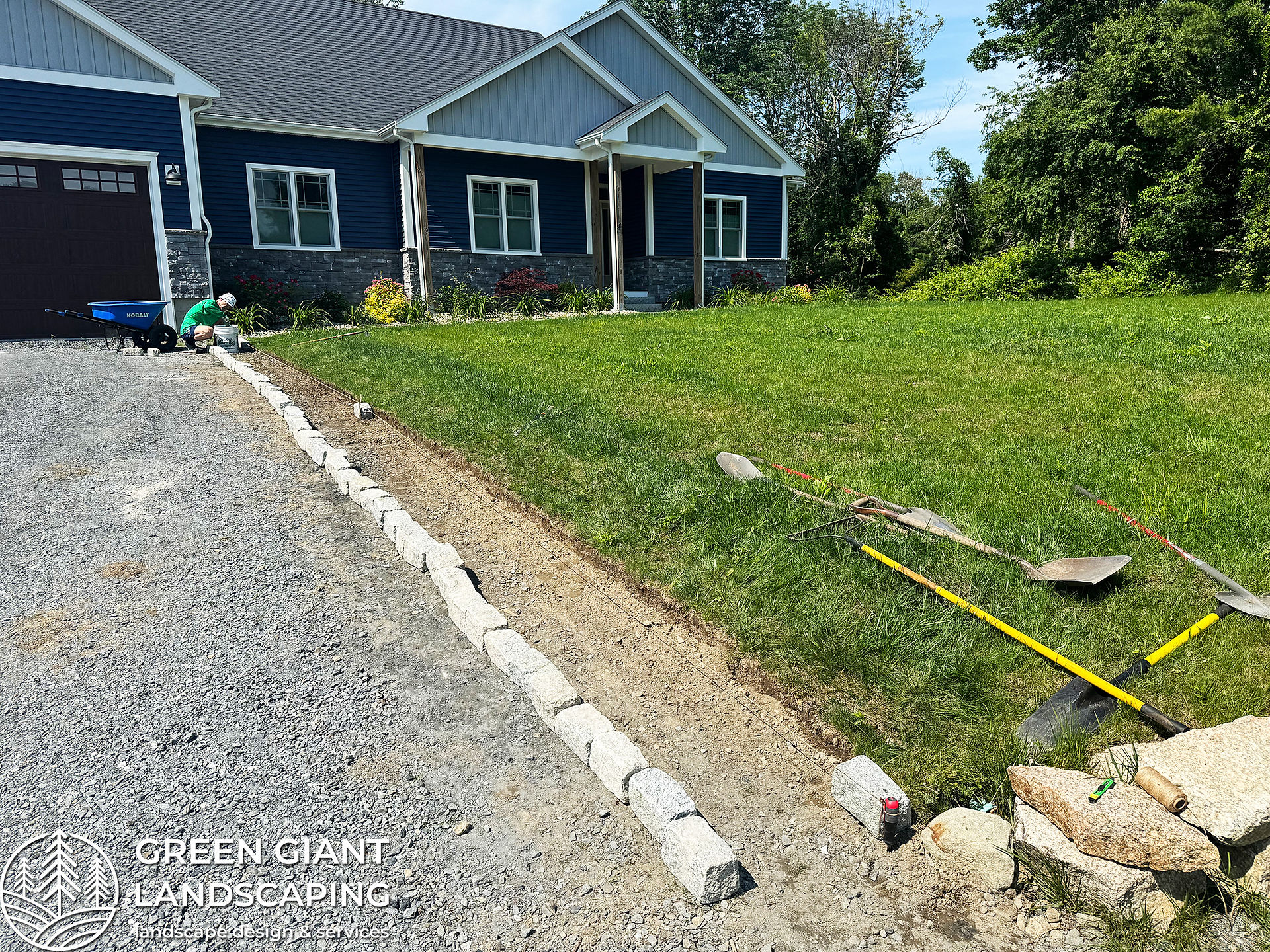Installing granite cobblestone edging in a concrete bed along a garden border in Massachusetts.