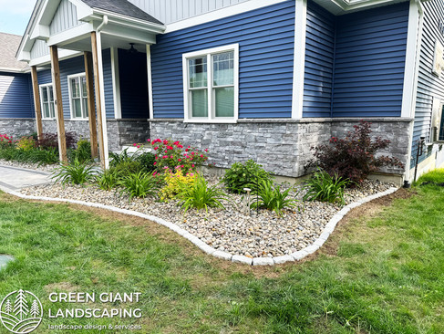 Professional granite cobblestone edging installation in a Massachusetts backyard during spring cleanup.
