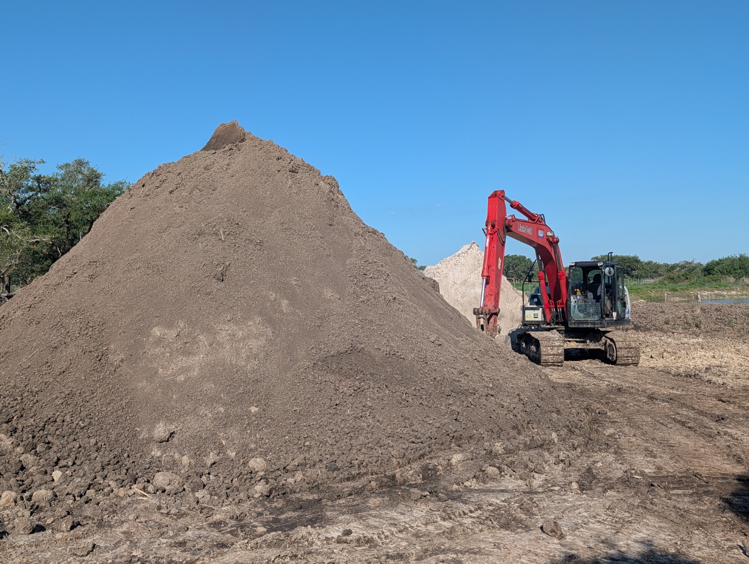 Sandy loam stockpile with excavator at AAA Digs It