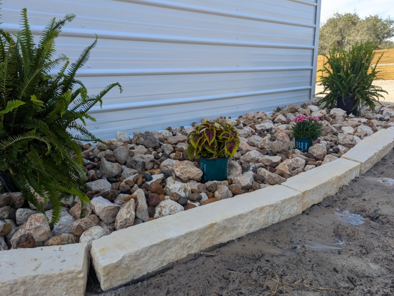 Installed 3–5 inch limestone riprap mixed with 1–2 inch Realitos river rock