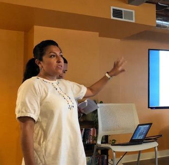 A woman gestures to a monitor