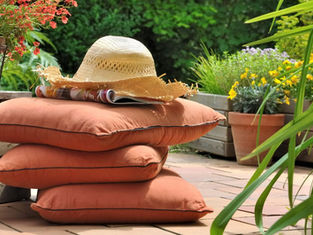 Outdoor pillow cushions on a deck with plants and flowers