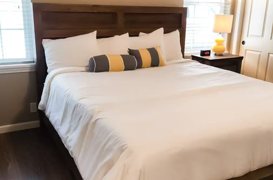 bed with white comforter and grey yellow pillows
