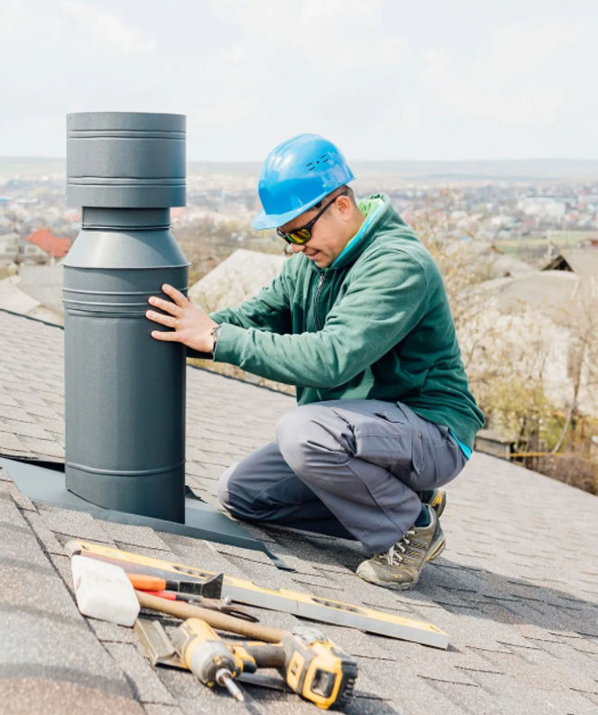 Worker installing chimney pipe on roof