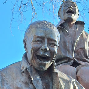 estátua de um homem e um rapaz a rir, no banco de um jardim