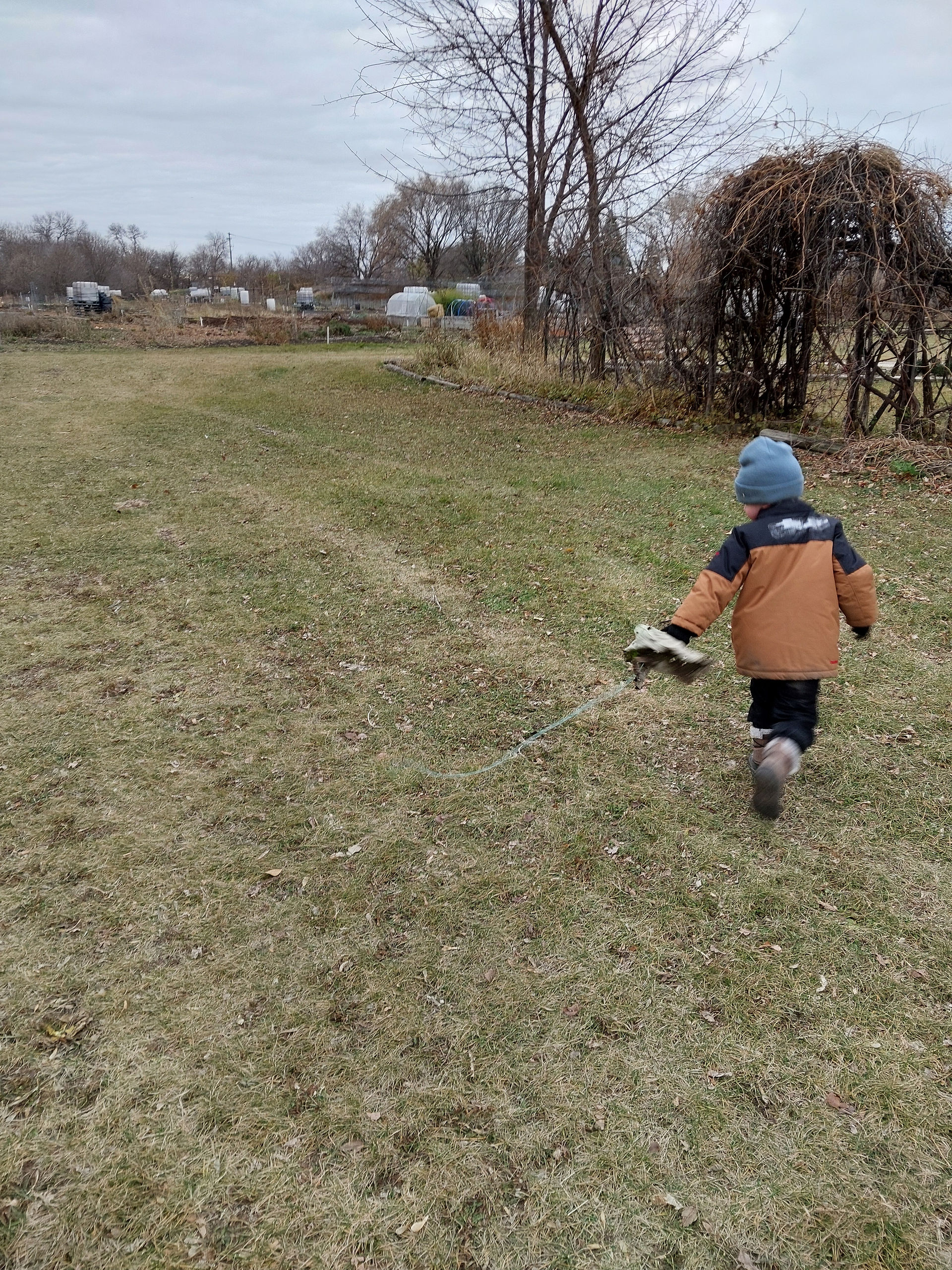A photo of a child running outside holding a string with a leaf tied to it