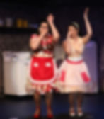 Performers singing and dancing on stage at the Wohlfahrt Haus Dinner Theatre