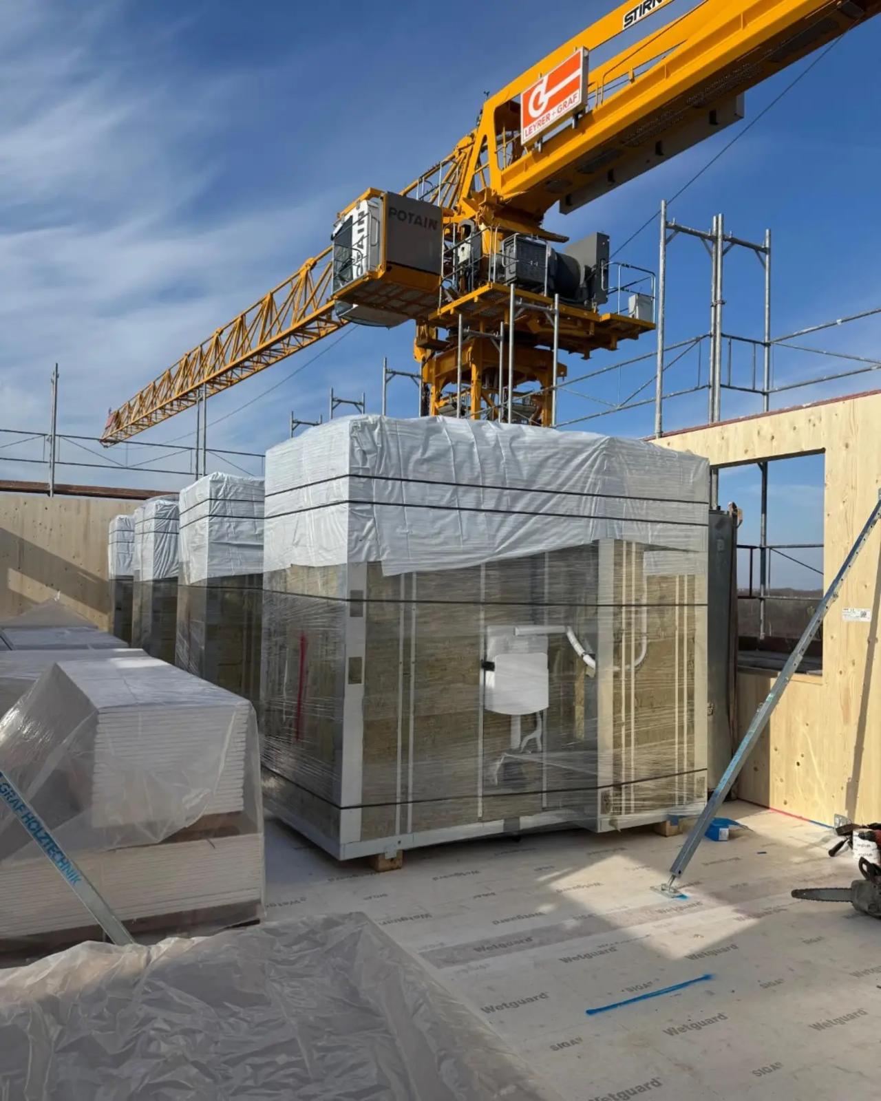 Verpackte Fertigbäder auf dem Holzdeck unter dem Baukran