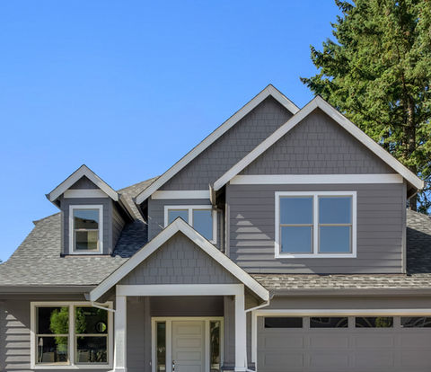 Suburban home exterior on bright sunny day, with large yard and covered porch