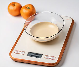 Moderne digitale Küchenwaage mit Glasschale, daneben frische Mandarinen auf weißem Hintergrund