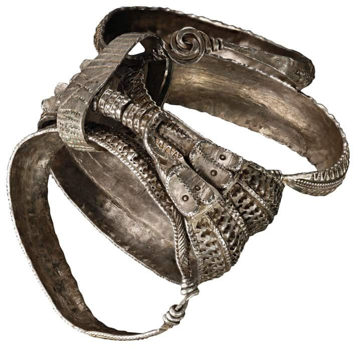 Livros Vikings | Pulseira metálica prateada e ornamentada, com trama e espirais, sobre fundo branco.