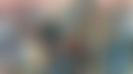 Livros Vikings | Uma ilustração detalhada mostrando um grupo de guerreiros vikings. No centro, um guerreiro veterano com barba branca e elmo de proteção facial proeminente segura um machado de batalha. Ele usa cota de malha e capa de pele. À sua direita, um guerreiro mais jovem segura um escudo azul redondo e lança. Outros guerreiros estão à esquerda. O fundo mostra uma praia com navios viking (langskip) e atividades de desembarque ao pôr do sol.