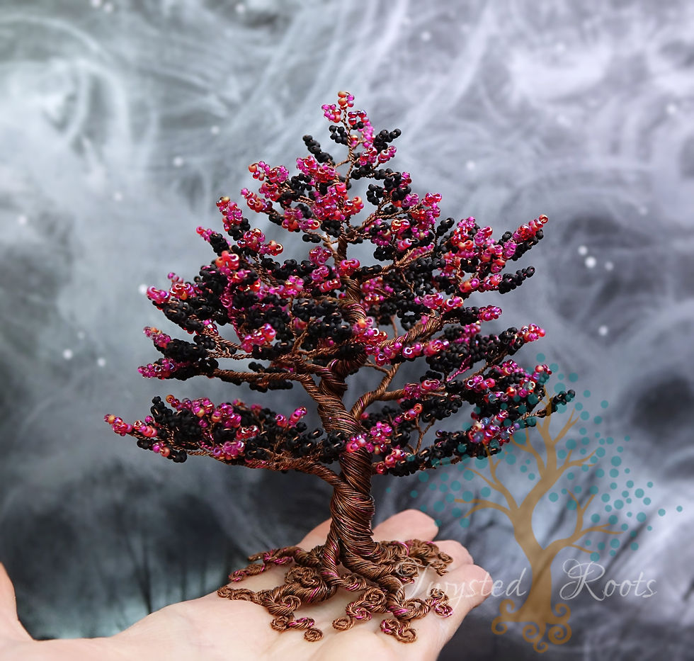 Thumbnail: Black and raspberry red bead and wire tree sitting on an upturned hand
