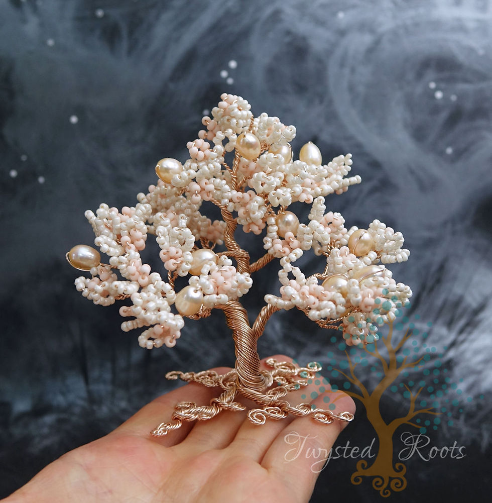 Thumbnail: Cream, peach and rose gold bead and wire tree sitting on the fingers of an upturned hand