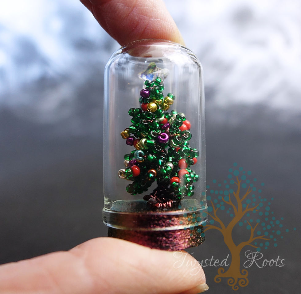 Thumbnail: Holding a glass dome between finger and thumb. Dome contains a tiny bead and wire Christmas tree