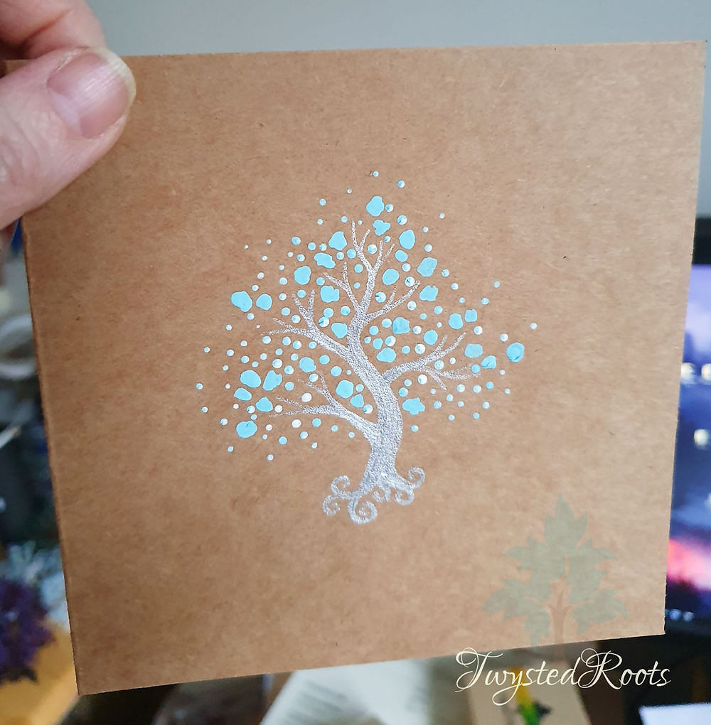 Brown card with a painting of a silver and blue tree on it by Twysted Roots