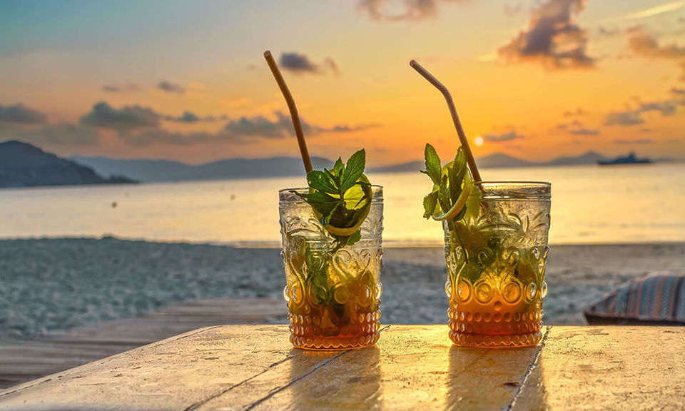 Two refreshing mojitos on table with the beach and sunset background