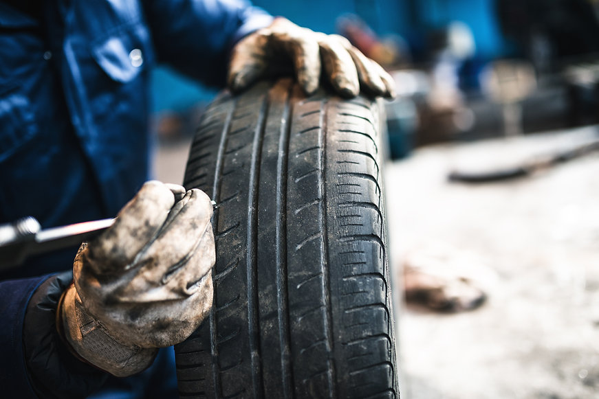 Image shows a mechanic fixing a tyre.