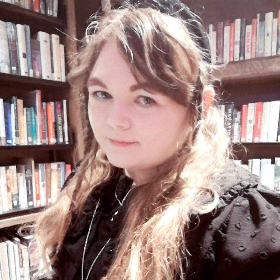 A portrait of E.C. Hibbs, an author with long, wavy light brown hair, wearing a black, textured blouse and a black headband. She is standing in front of bookshelves filled with various books, giving a soft, thoughtful expression. The background of the image features a warm, cozy library setting, reflecting her literary and artistic persona.