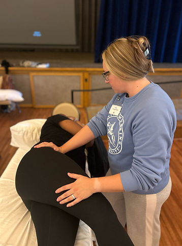 Therapist performing bodywork on client's hip and lower back.