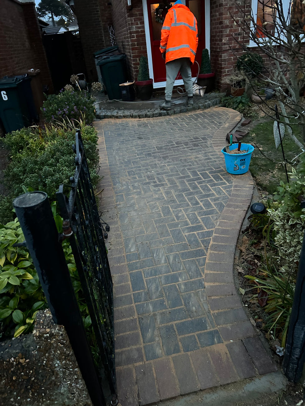 a person standing on a brick walkway next to a blue bucket that says ' aa ' on it