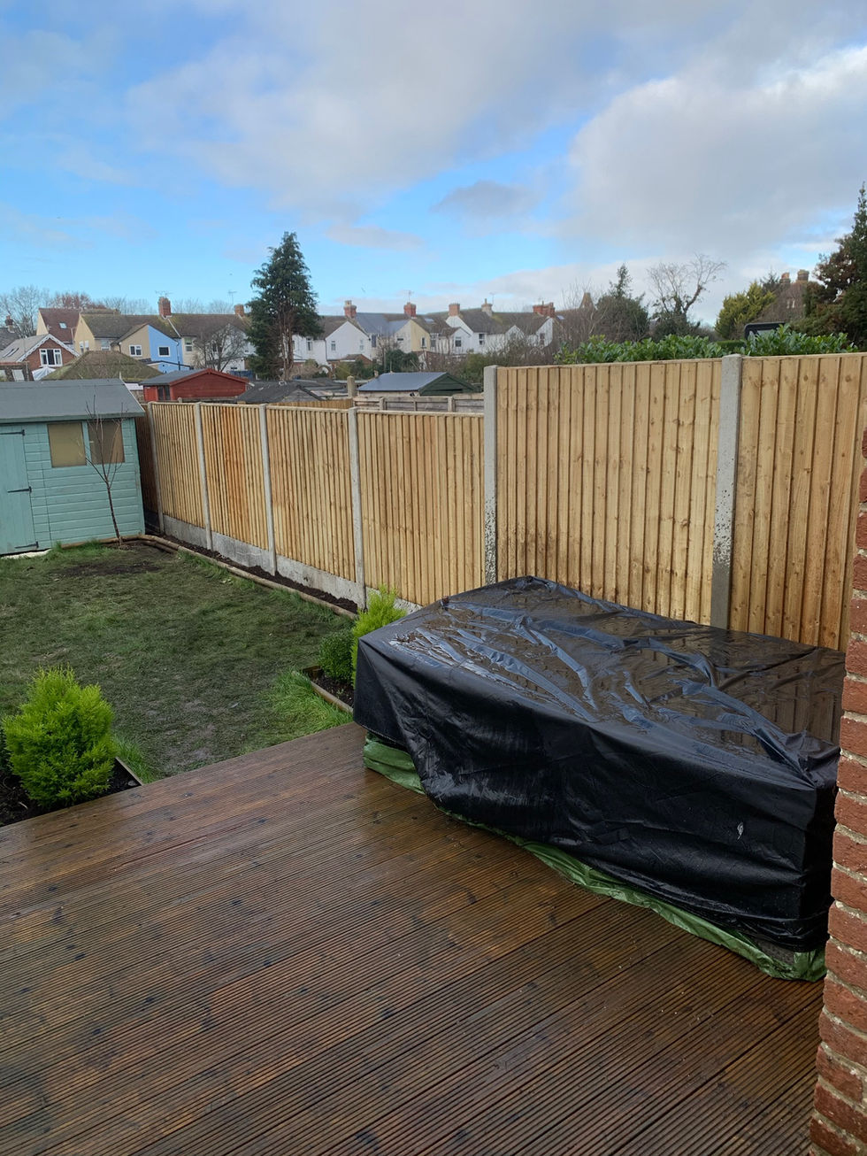 a wooden fence surrounds a backyard with a green shed in the background