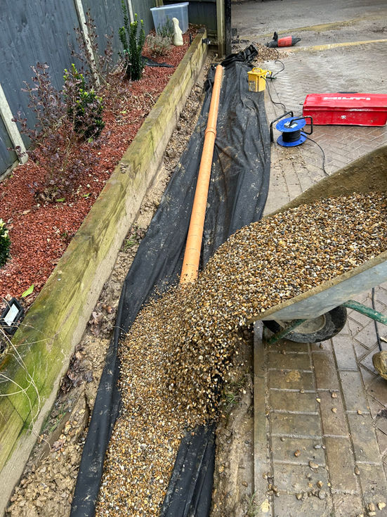 a wheelbarrow is filled with gravel next to a pipe