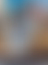 Balloons shaped like turkeys float above a large parade in a city. Crowds line the street, with autumn trees and tall buildings in the background.