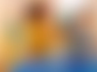 Two children playing with colorful rainbow blocks at a blue table, with a teepee in the background. The girl wears yellow, and the boy wears plaid.