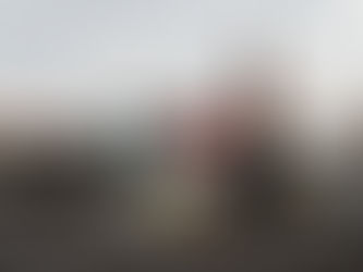 Wine glass and bottle on gravel road, surrounded by litter. Background shows blurred car and cloudy sky, creating a somber mood.