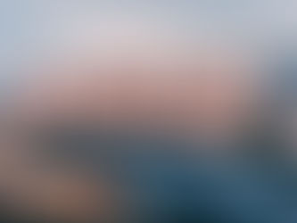 Parking lot with cars in front of a large building with "TESLA" in bold letters. The sky is clear with a soft sunset glow.