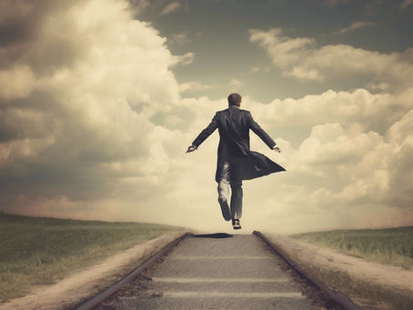 A man in a suit jumps on a deserted road towards a cloudy sky, evoking freedom and determination. The scene is one of vastness and optimism.