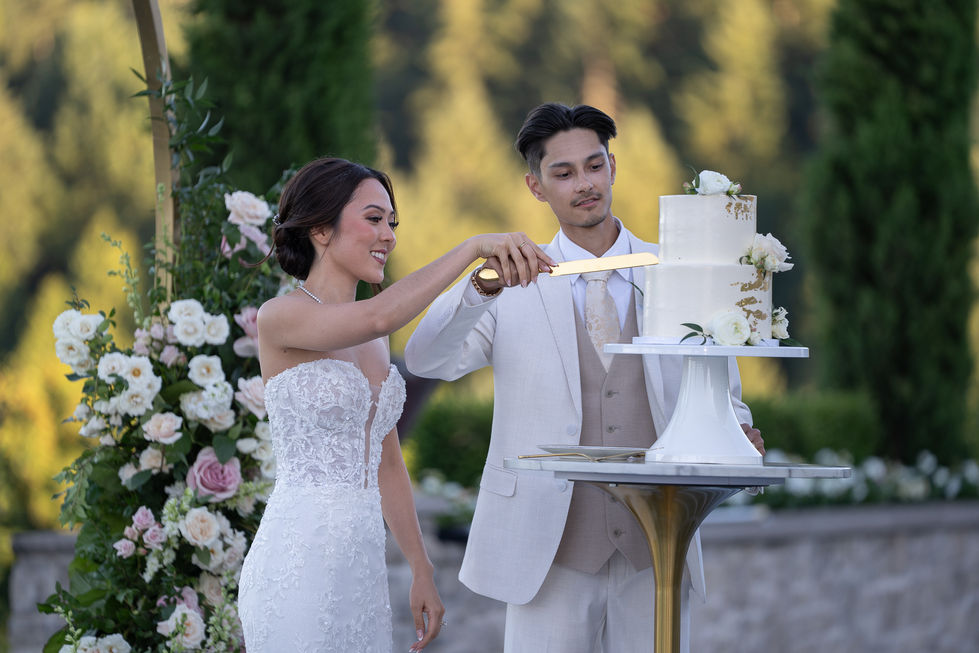 Bride and groom cutting wedding cake outdoors.