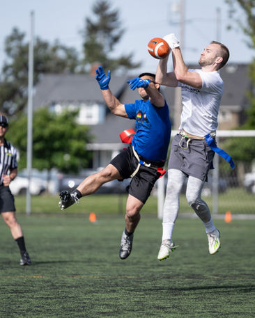 Two people playing flag football, jumping for ball.