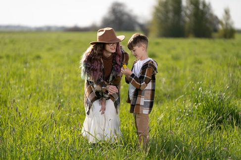 Woman and child in a grassy field, smiling.