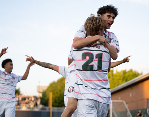 Two soccer players celebrating a goal on the field.