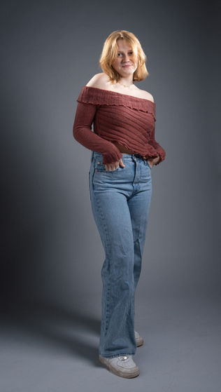 Person in off-shoulder top and jeans, standing pose.