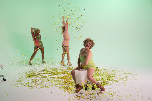 Four people celebrating with confetti in colorful outfits.