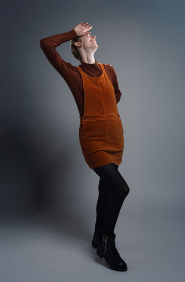Person posing in orange outfit against gray background.