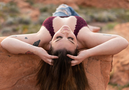 Woman reclining on rock, outdoors, eyes closed.