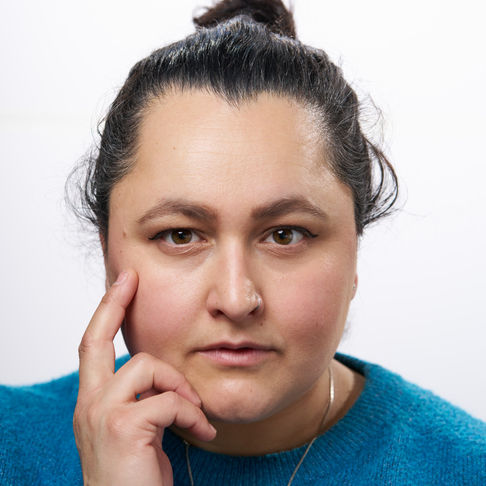 A person with a thoughtful expression, wearing a blue sweater.