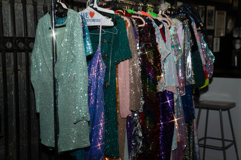 Sparkling, colorful dresses hanging on a clothes rack.