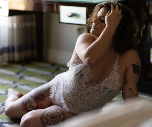 Person in lace outfit sitting on patterned floor.