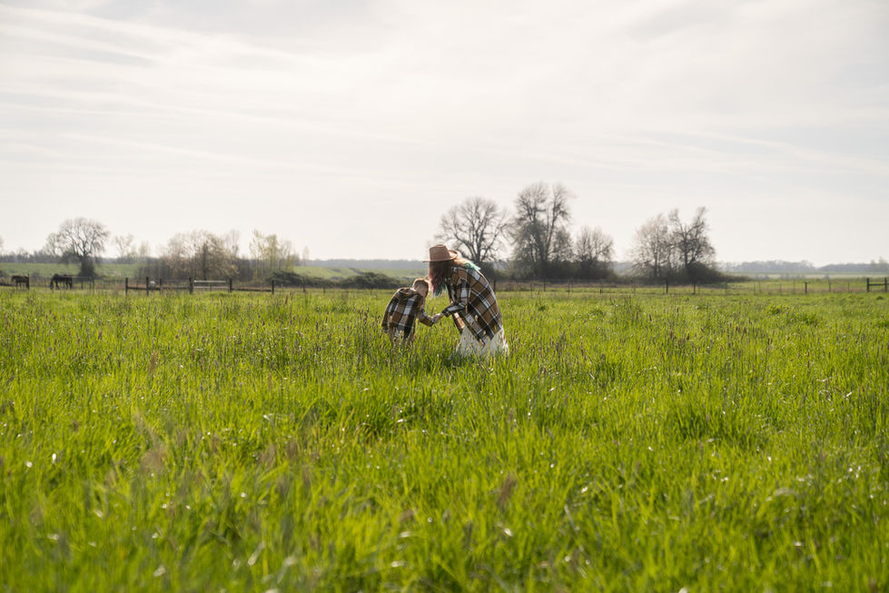 Mother and child in a grassy field, embracing.