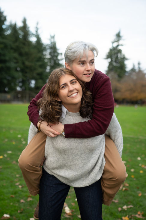 Two people smiling, enjoying a piggyback ride outdoors.