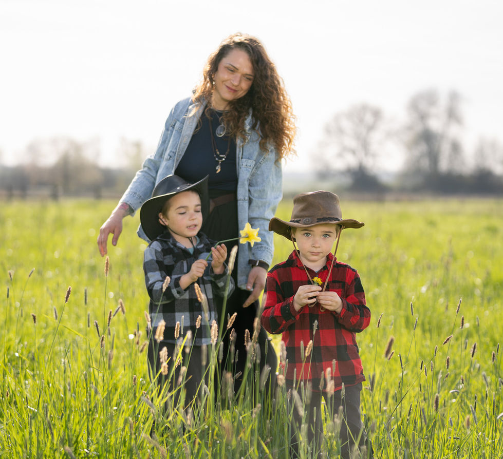 Woman and two children in a grassy field.