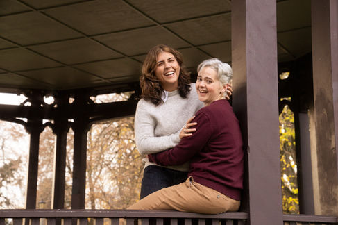 Two people smiling, sitting on a wooden structure.