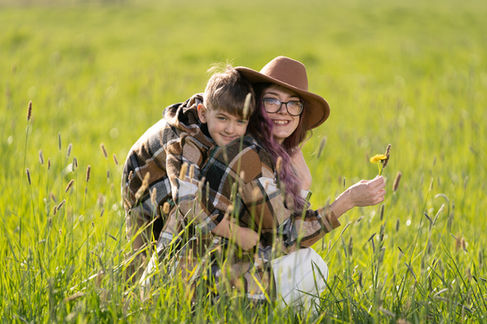 Smiling woman and child in a grassy field.