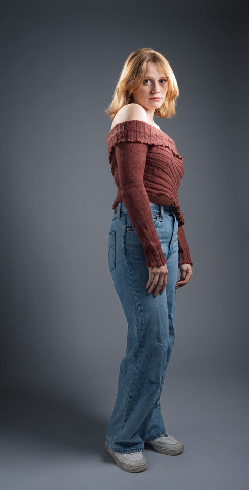 Person in red top and jeans, standing sideways.