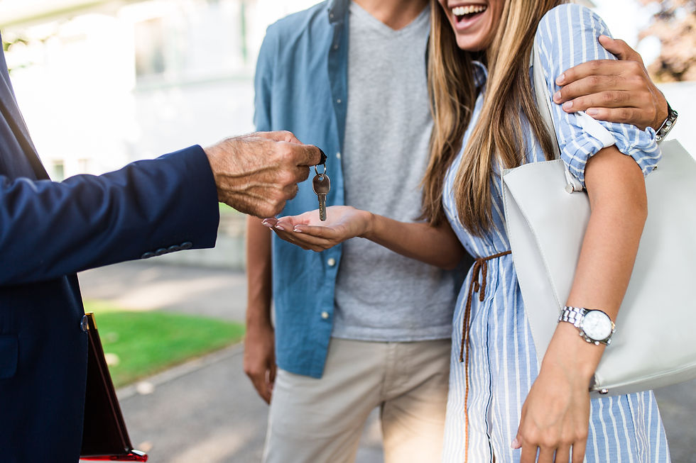 Northeast Ohio real estate agent handing house keys to a smiling couple buying a home.